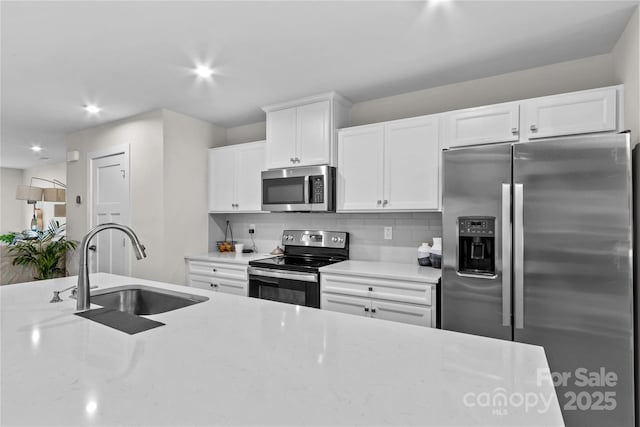 124 Kristin View Ln Unit C, Troutman, NC 28166 - kitchen with appliances with stainless steel finishes, a sink, backsplash, white cabinets, and light stone countertops