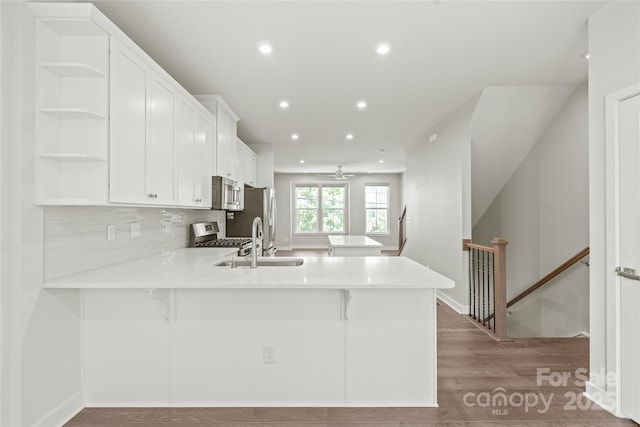 420 E 16th St, Charlotte, NC 28206 - kitchen with appliances with stainless steel finishes, a sink, a peninsula, wood finished floors, and white cabinets