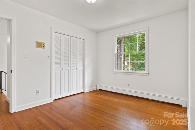 841 12th Ave NW, Hickory, NC 28601 - unfurnished bedroom featuring baseboard heating, wood finished floors, a closet, and baseboards