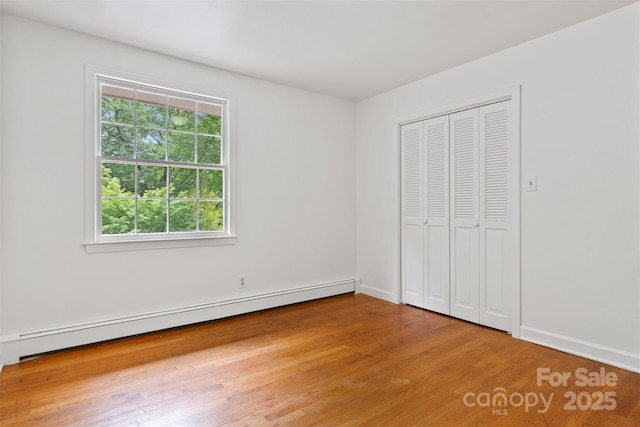 841 12th Ave NW, Hickory, NC 28601 - unfurnished bedroom with a baseboard heating unit, wood finished floors, baseboards, and a closet