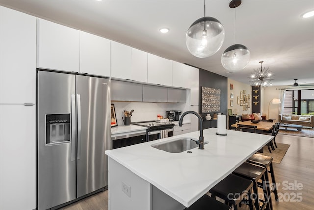 4520 Radler Ct, Charlotte, NC 28217 - kitchen featuring appliances with stainless steel finishes, a sink, wood finished floors, a kitchen island with sink, and light countertops