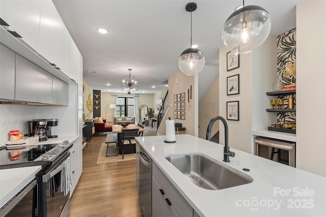 4520 Radler Ct, Charlotte, NC 28217 - kitchen with a sink, appliances with stainless steel finishes, light countertops, pendant lighting, and wood finished floors