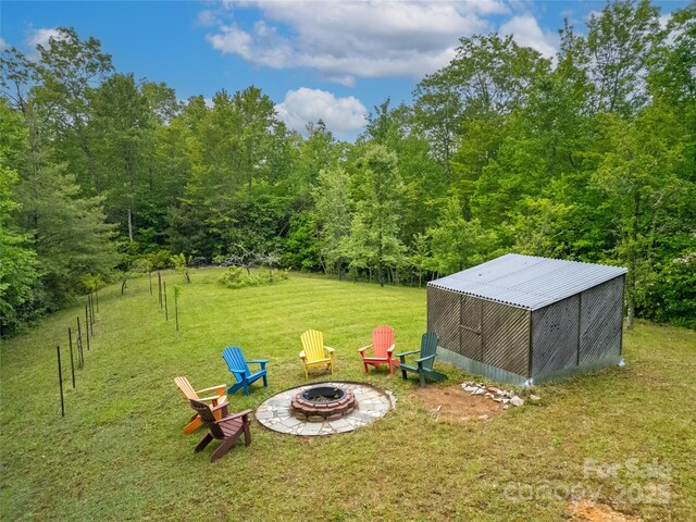 229 Hubbard Hollow Rd, Rosman, NC 28772 - view of grassy yard with an outdoor fire pit, an outbuilding, an outdoor structure, and a forest view
