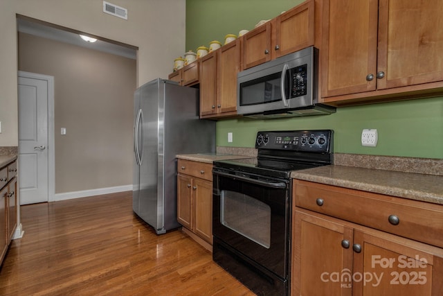 32 White Fox Dr, Fletcher, NC 28732 - kitchen with appliances with stainless steel finishes, brown cabinets, light wood-style flooring, and baseboards