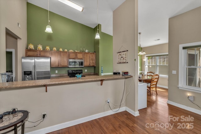 32 White Fox Dr, Fletcher, NC 28732 - kitchen with appliances with stainless steel finishes, high vaulted ceiling, brown cabinetry, dark wood-style flooring, and a breakfast bar
