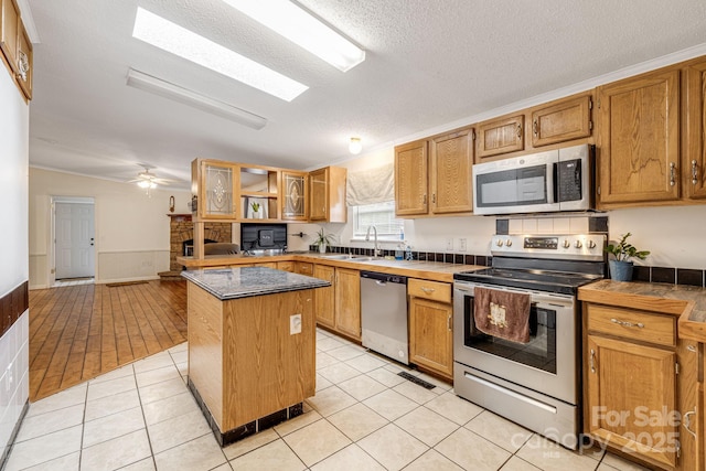 553 New Hope Rd, Rutherfordton, NC 28139 - kitchen with stainless steel appliances, a sink, a center island, a wainscoted wall, and glass insert cabinets