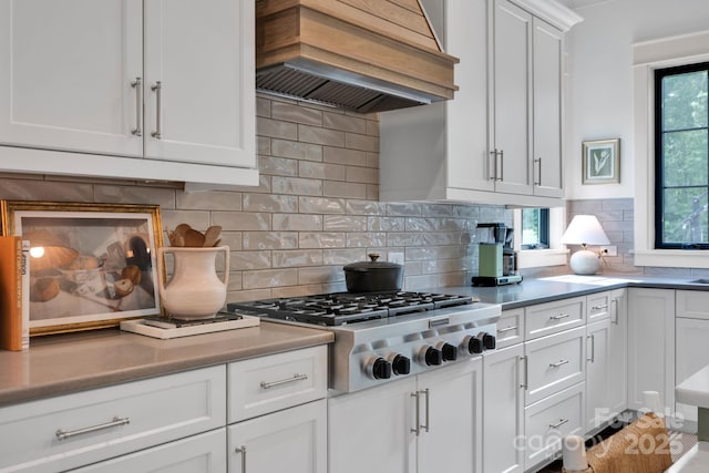 14105 Ryker Way, Davidson, NC 28036 - kitchen with custom range hood, stainless steel gas stovetop, white cabinetry, and backsplash