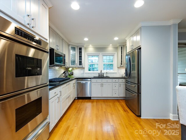 6941 Queensberry Dr, Charlotte, NC 28226 - kitchen featuring appliances with stainless steel finishes, crown molding, dark countertops, glass insert cabinets, and decorative backsplash