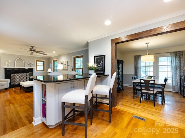 6941 Queensberry Dr, Charlotte, NC 28226 - kitchen with light wood-type flooring, ornamental molding, a breakfast bar, ceiling fan, and decorative light fixtures