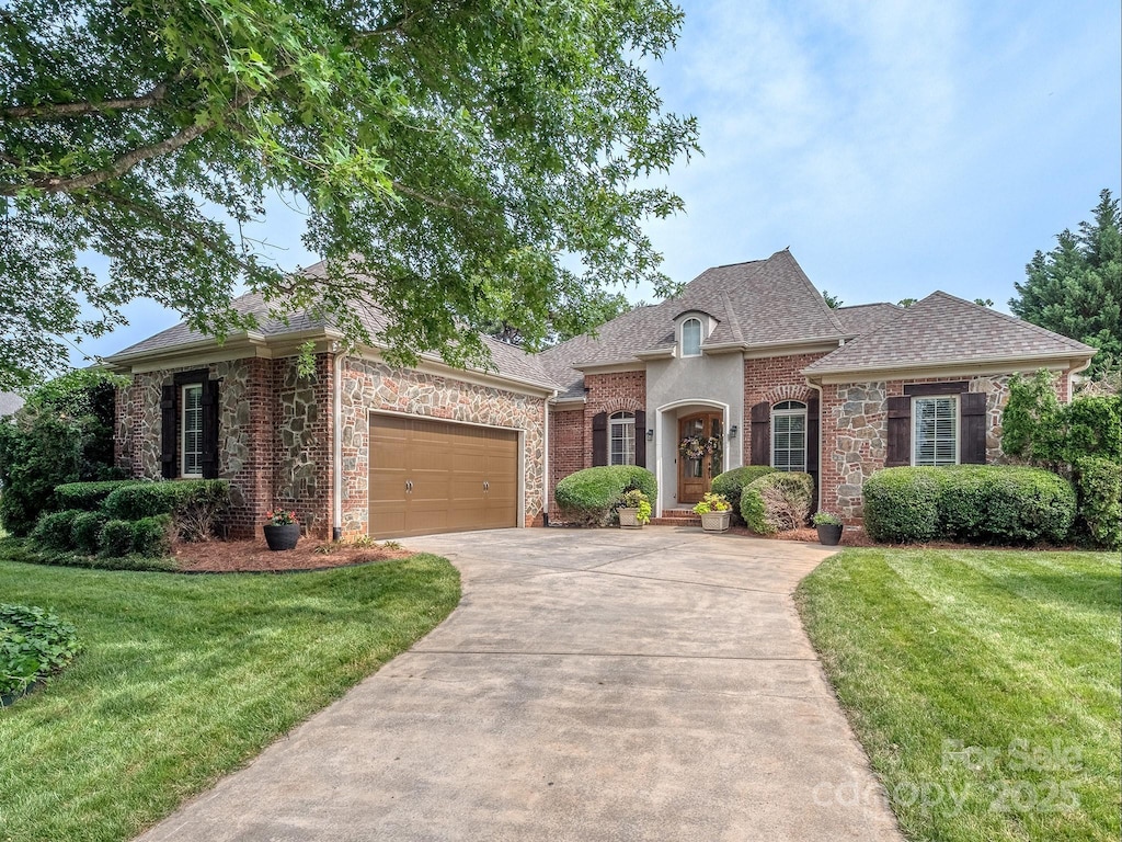 705 Woburn Abbey Dr, Fort Mill, SC 29715 - french provincial home featuring driveway, a garage, a front lawn, and stone siding
