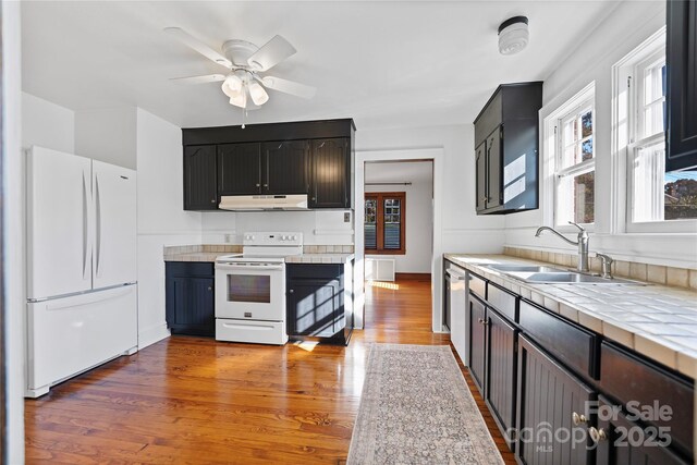 495 Fairview Rd, Asheville, NC 28803 - kitchen with white appliances, under cabinet range hood, a sink, tile counters, and wood finished floors