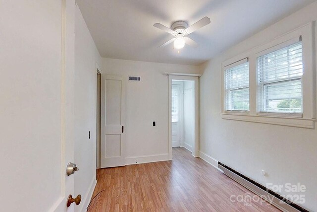495 Fairview Rd, Asheville, NC 28803 - unfurnished bedroom featuring a baseboard radiator, light wood-style flooring, baseboards, and a ceiling fan