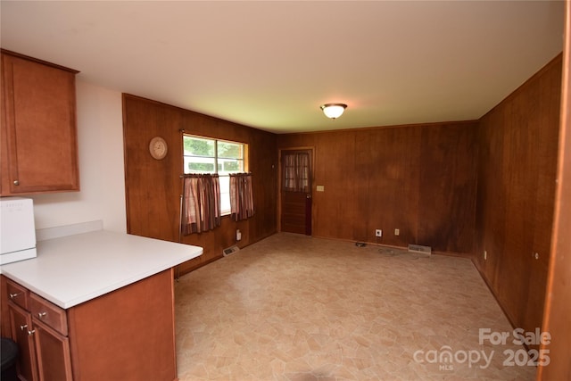 908 Ravendale Dr, Charlotte, NC 28216 - kitchen featuring wooden walls, brown cabinetry, light countertops, stone finish floors, and open floor plan