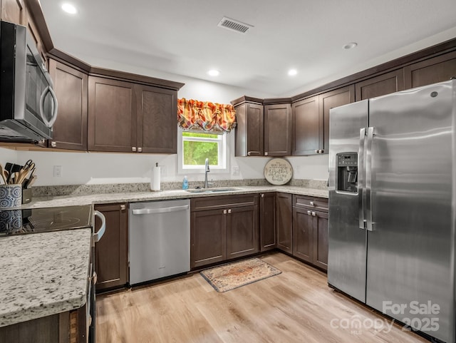 125 Woodland Cir, Rutherfordton, NC 28139 - kitchen featuring appliances with stainless steel finishes, a sink, dark brown cabinets, light wood-type flooring, and light stone countertops