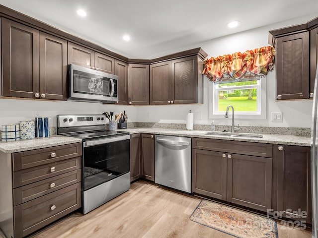 125 Woodland Cir, Rutherfordton, NC 28139 - kitchen featuring appliances with stainless steel finishes, a sink, dark brown cabinetry, light wood-style floors, and light stone counters