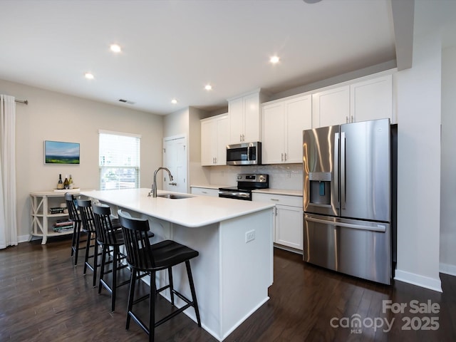 1839 Shumard Ln, Charlotte, NC 28205 - kitchen featuring appliances with stainless steel finishes, a center island with sink, dark wood-style flooring, a kitchen bar, and recessed lighting