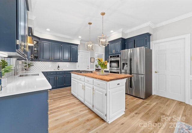 1115 Maremont Ct, Matthews, NC 28104 - kitchen with stainless steel appliances, a sink, blue cabinetry, wood counters, and a center island