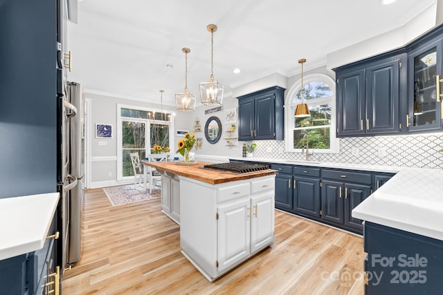 1115 Maremont Ct, Matthews, NC 28104 - kitchen with stainless steel gas cooktop, blue cabinetry, butcher block counters, ornamental molding, and a kitchen island