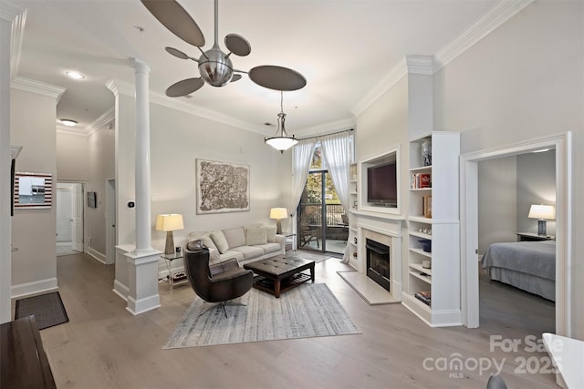 718 W Trade St Unit 105, Charlotte, NC 28202 - living area with decorative columns, ceiling fan, wood finished floors, crown molding, and a fireplace with raised hearth