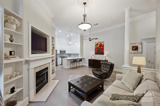718 W Trade St Unit 105, Charlotte, NC 28202 - living room with ornate columns, ornamental molding, built in features, light wood-type flooring, and a premium fireplace