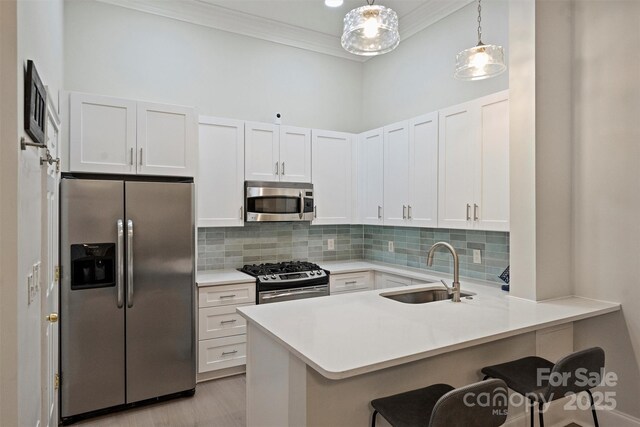 718 W Trade St Unit 105, Charlotte, NC 28202 - kitchen featuring stainless steel appliances, a breakfast bar, ornamental molding, white cabinets, and light countertops