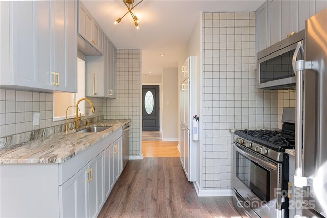 110 Annandale Ave, Asheville, NC 28801 - kitchen with appliances with stainless steel finishes, a sink, wood finished floors, backsplash, and light stone countertops