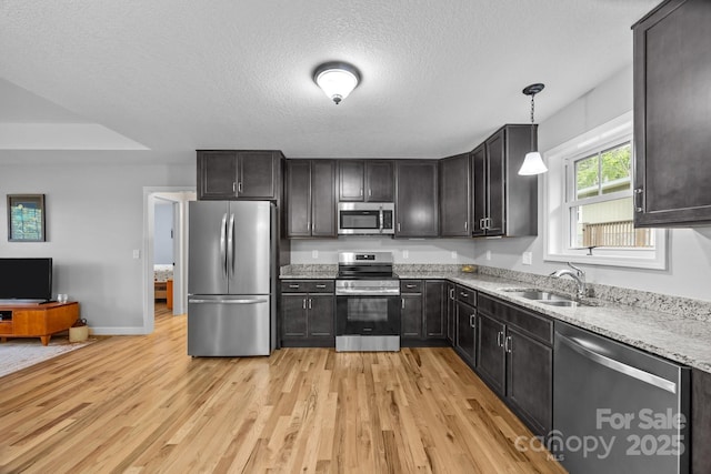 17 Laurel Rd, Arden, NC 28704 - kitchen featuring appliances with stainless steel finishes, a sink, light wood-style floors, light stone counters, and a textured ceiling