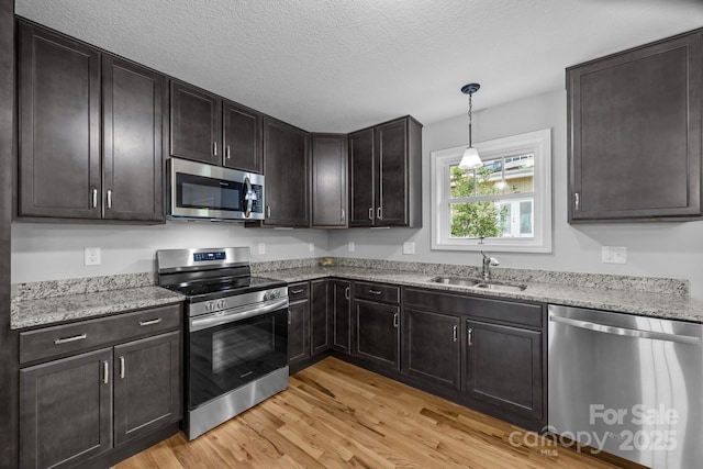 17 Laurel Rd, Arden, NC 28704 - kitchen featuring appliances with stainless steel finishes, light wood-style floors, a sink, light stone countertops, and a textured ceiling