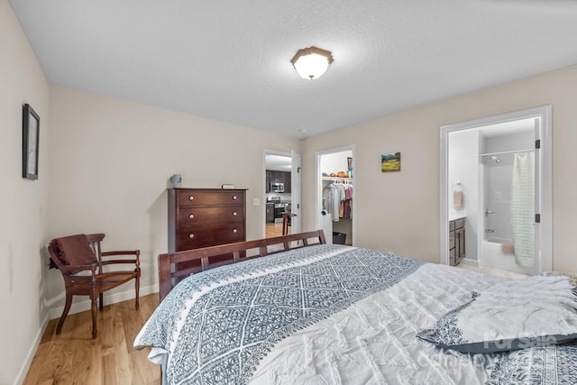 17 Laurel Rd, Arden, NC 28704 - bedroom with wood finished floors, baseboards, a walk in closet, a closet, and connected bathroom
