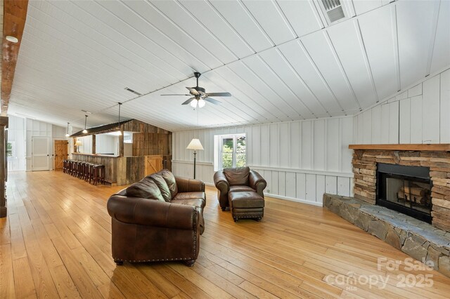 1283 Leafstone Cir, Sylva, NC 28779 - living room featuring hardwood / wood-style floors, vaulted ceiling, a fireplace, a ceiling fan, and wood walls