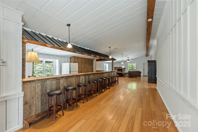 1283 Leafstone Cir, Sylva, NC 28779 - indoor dry bar featuring freestanding refrigerator, light wood-type flooring, hanging light fixtures, a stone fireplace, and wooden walls
