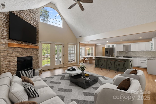 9372 Island Point Rd, Sherrills Ford, NC 28673 - living room with high vaulted ceiling, ceiling fan, light wood-style flooring, a textured ceiling, and a fireplace