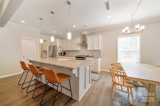2035 Beacon Ave, Monroe, NC 28110 - kitchen with stainless steel appliances, wall chimney exhaust hood, backsplash, ornamental molding, and a chandelier