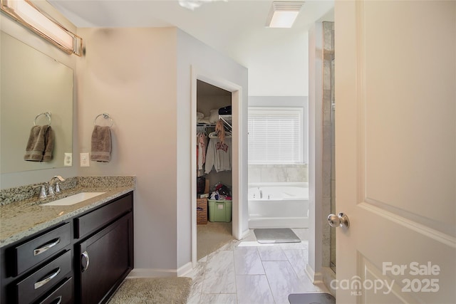 2035 Beacon Ave, Monroe, NC 28110 - bathroom with vanity, a walk in closet, a bath, marble look tile flooring, and baseboards