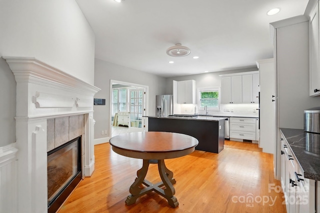 7725 Whitmire Ln, Mint Hill, NC 28227 - kitchen featuring stainless steel appliances, a sink, a tiled fireplace, a center island, and light wood-style flooring