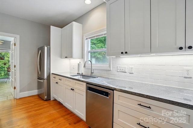 7725 Whitmire Ln, Mint Hill, NC 28227 - kitchen with stainless steel appliances, a sink, dark stone countertops, light wood-style floors, and baseboards