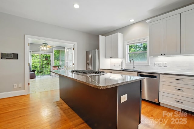 7725 Whitmire Ln, Mint Hill, NC 28227 - kitchen featuring appliances with stainless steel finishes, a sink, a center island, decorative backsplash, and a ceiling fan