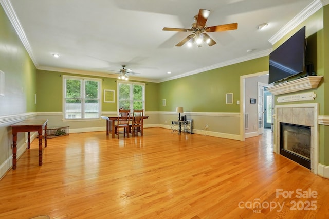 7725 Whitmire Ln, Mint Hill, NC 28227 - living room with a ceiling fan, light wood-style flooring, crown molding, a tiled fireplace, and baseboards