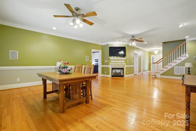 7725 Whitmire Ln, Mint Hill, NC 28227 - dining area with a ceiling fan, stairs, a tiled fireplace, ornamental molding, and light wood-style flooring