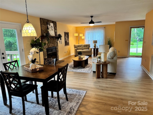 1228 Hidden Creek Cir, Hickory, NC 28602 - dining room with light wood-style floors, ceiling fan, a stone fireplace, and baseboards