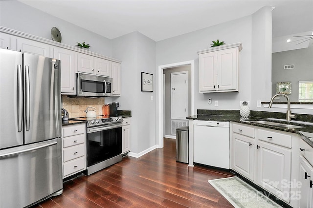 10449 Quiet Bay Ct, Charlotte, NC 28278 - kitchen featuring stainless steel appliances, a sink, dark wood-style flooring, backsplash, and white cabinetry