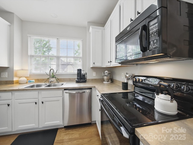 1061 Woodglen Ln, Matthews, NC 28104 - kitchen with black appliances, a sink, white cabinets, light countertops, and light wood-style flooring