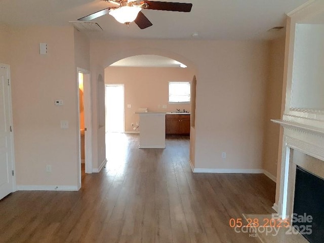 13441 Calloway Glen Dr, Charlotte, NC 28273 - unfurnished living room with arched walkways, a ceiling fan, light wood-type flooring, a fireplace, and baseboards