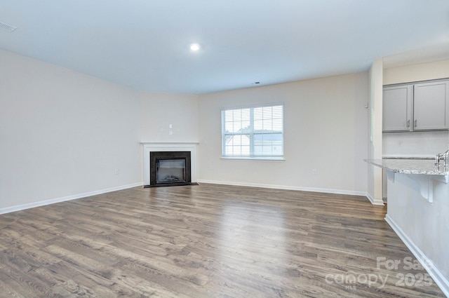 427 Carolina Hemlock Dr, Locust, NC 28097 - unfurnished living room with dark wood-style flooring, a glass covered fireplace, baseboards, and recessed lighting