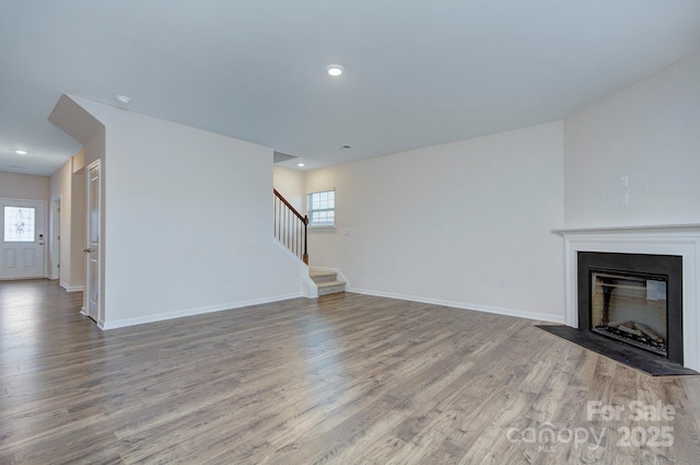 427 Carolina Hemlock Dr, Locust, NC 28097 - unfurnished living room with stairs, wood finished floors, baseboards, a glass covered fireplace, and recessed lighting