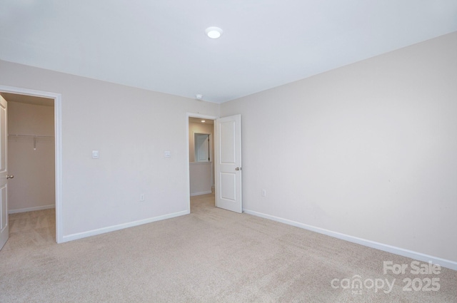 427 Carolina Hemlock Dr, Locust, NC 28097 - unfurnished bedroom featuring a walk in closet, light carpet, and baseboards