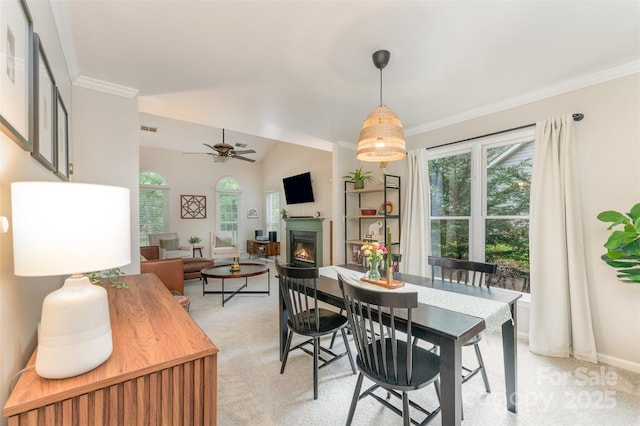 8624 Canter Post Dr, Charlotte, NC 28216 - dining area with light carpet, a warm lit fireplace, ornamental molding, a ceiling fan, and baseboards