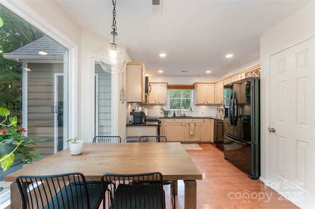 8624 Canter Post Dr, Charlotte, NC 28216 - kitchen featuring black appliances, light brown cabinetry, light wood-style floors, hanging light fixtures, and decorative backsplash