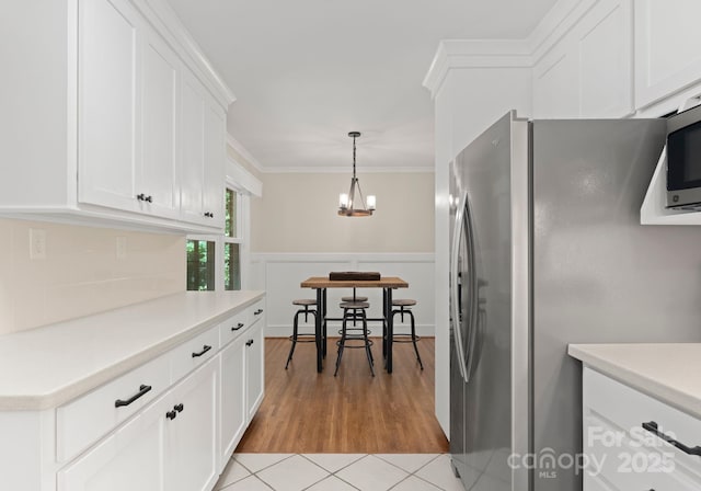 1226 Tarrington Ave, Charlotte, NC 28205 - kitchen featuring freestanding refrigerator, white cabinetry, light countertops, decorative backsplash, and a chandelier
