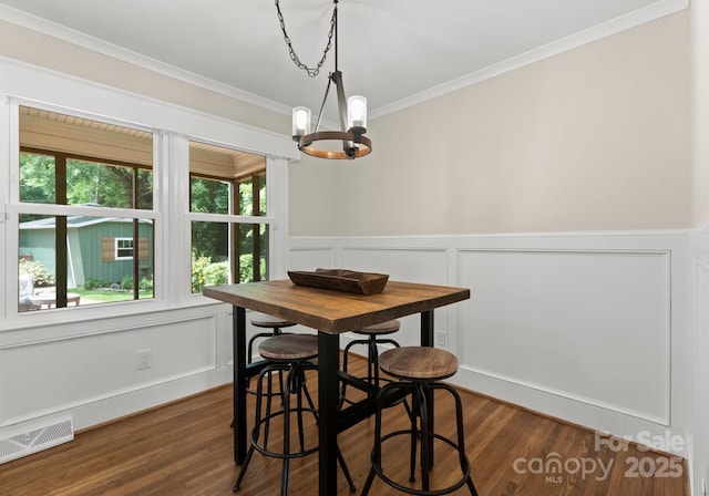 1226 Tarrington Ave, Charlotte, NC 28205 - dining area with a chandelier, dark wood-style flooring, crown molding, a decorative wall, and a wainscoted wall